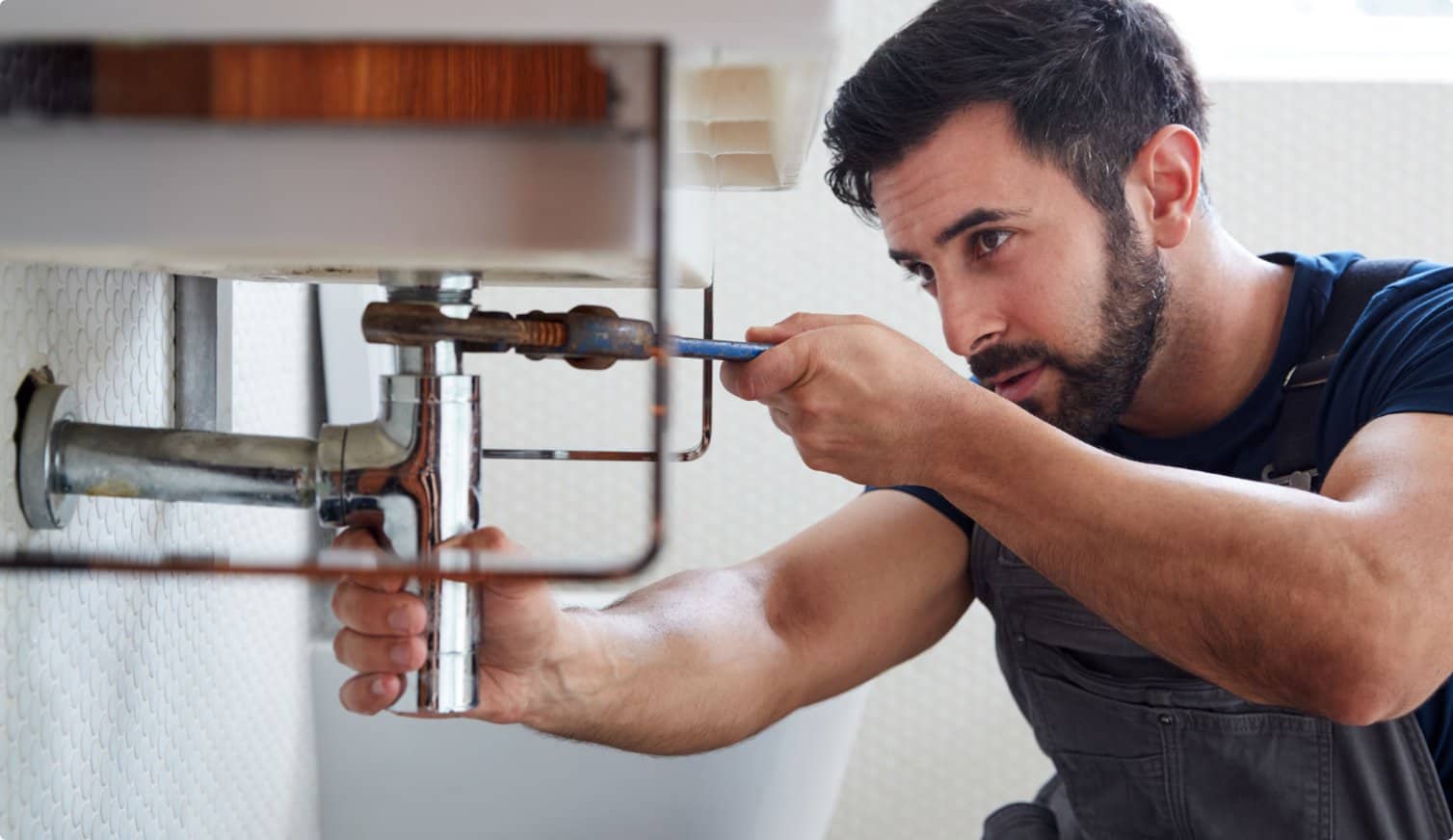 A plumber fixing a sink in a bathroom.